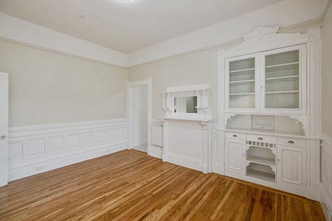 an empty kitchen with white cabinets and a wood floor