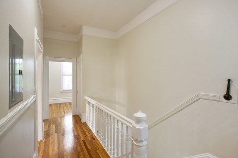 a landing with a white railing and a hallway with a window