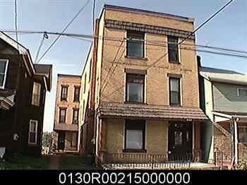 A brown building with a black door and windows sits between two other buildings.