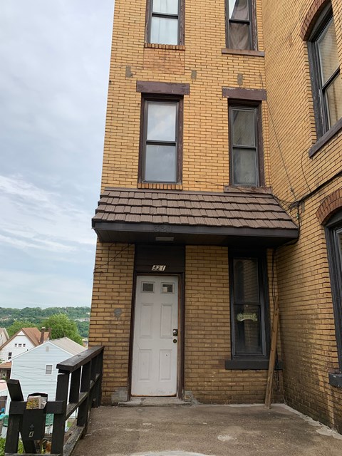 A brown brick building with a white door and windows.