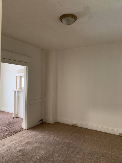 a living room with white walls and a ceiling light