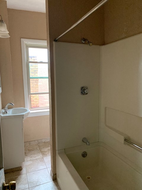 a bathroom with a tub and a sink and a window
