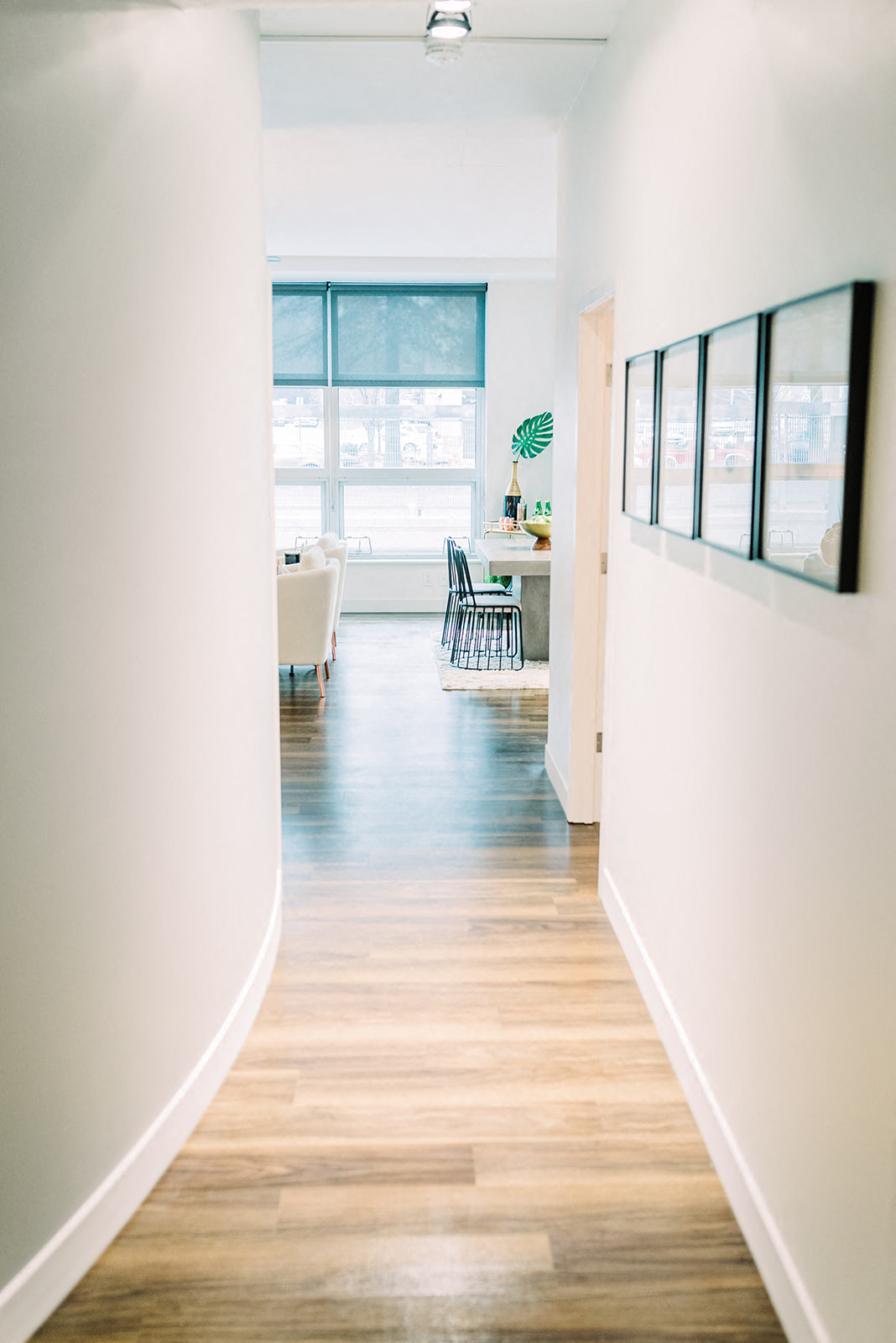 a hallway with white walls and wooden floors and a window