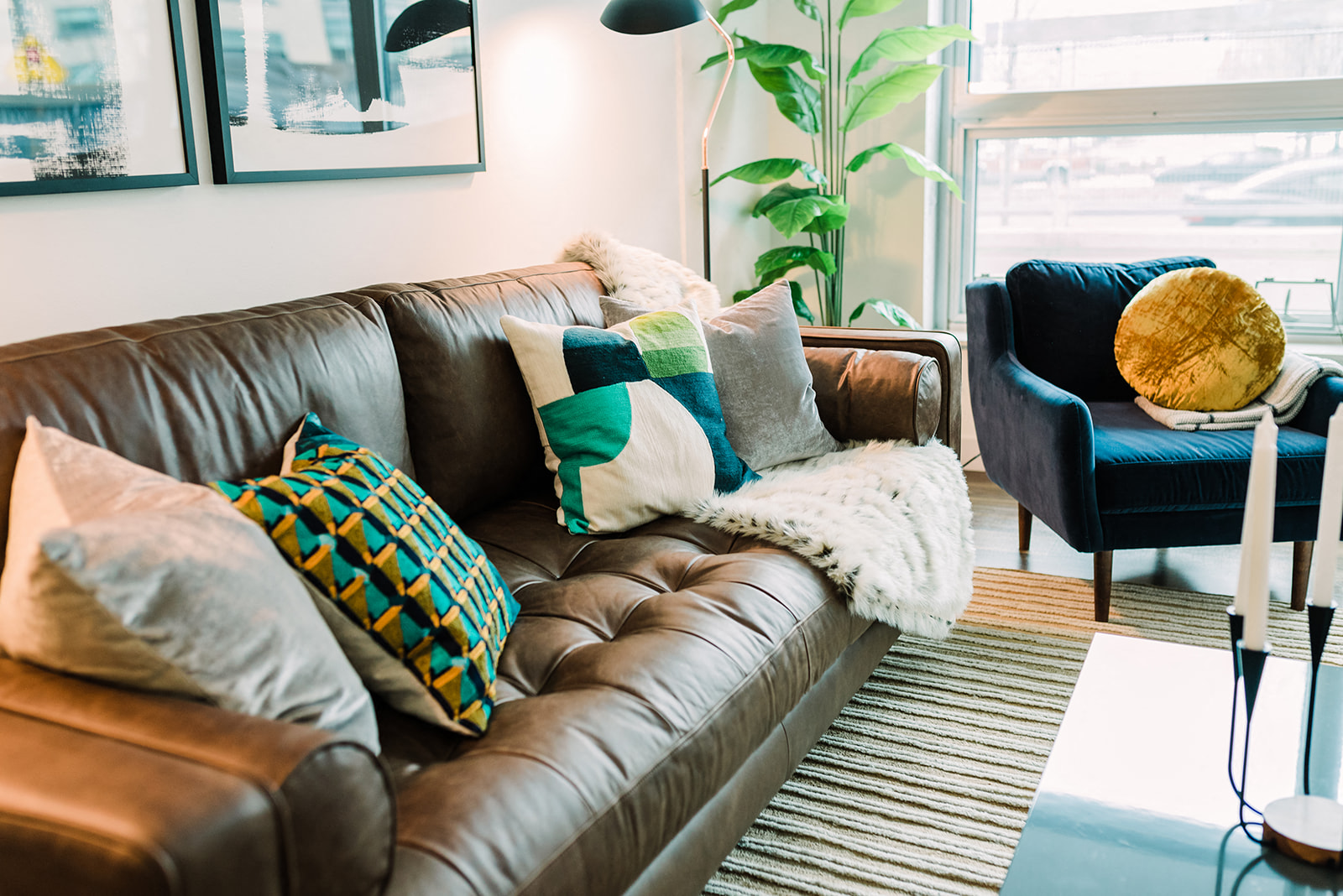 a living room with a brown leather couch and pillows