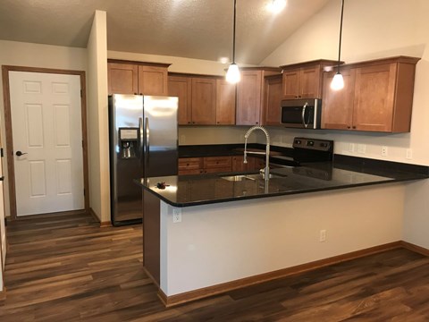 A kitchen with wooden cabinets and a black countertop.