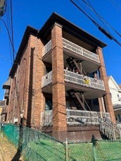 A large brick building with a balcony and a green fence in front.