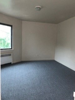 an empty room with a window and a blue carpet