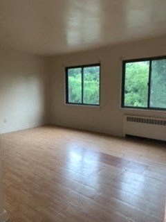 an empty living room with a wood floor and windows