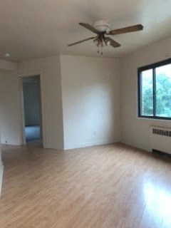 an empty living room with a ceiling fan and wood floors