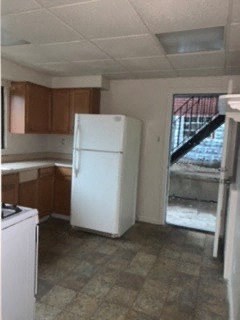 an empty kitchen with a white refrigerator in it