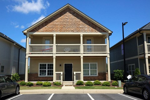 a yellow house with a balcony and cars parked in front of it