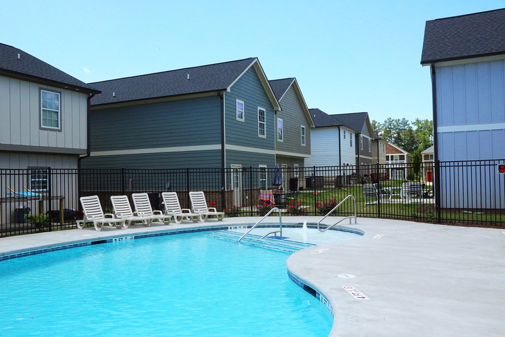 a swimming pool with chaise lounge chairs in front of apartment buildings