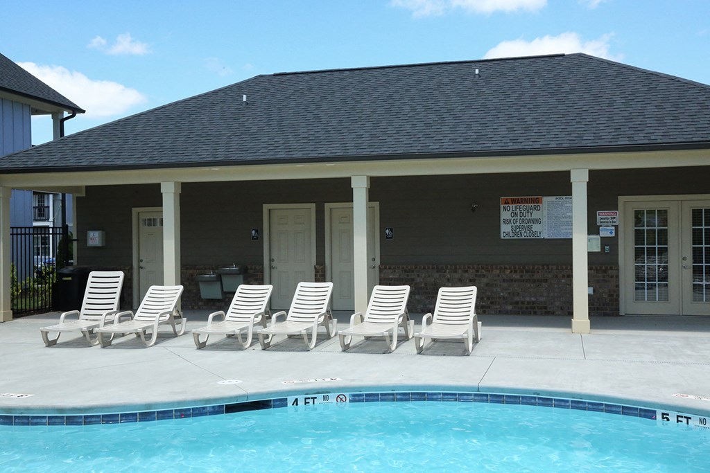 a covered patio with chairs next to a swimming pool