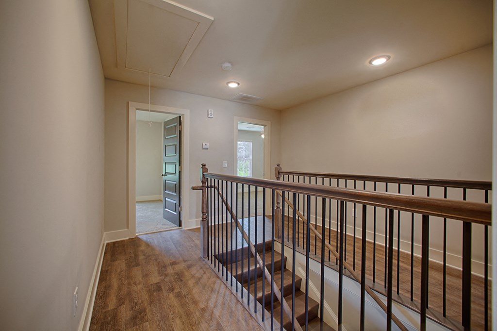 the upstairs landing of a house with stairs and a railing