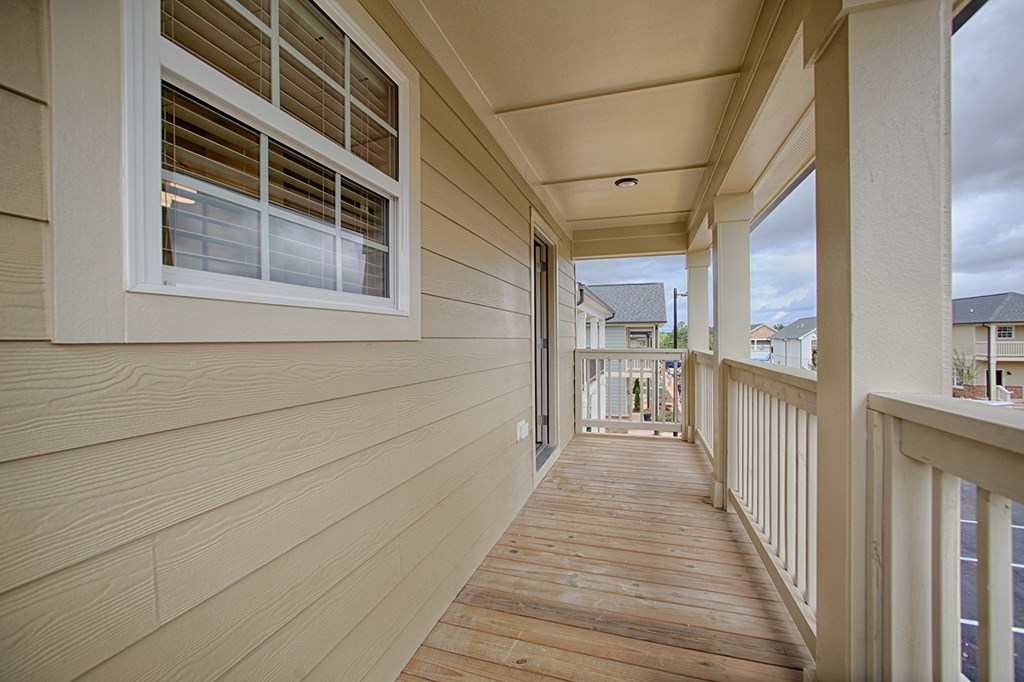 a long porch with wood floors and white railings