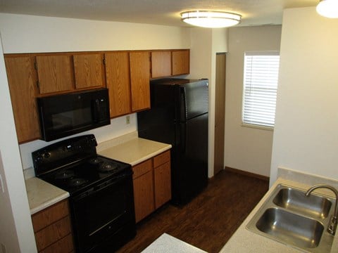 a kitchen with black appliances and wooden cabinets and a sink