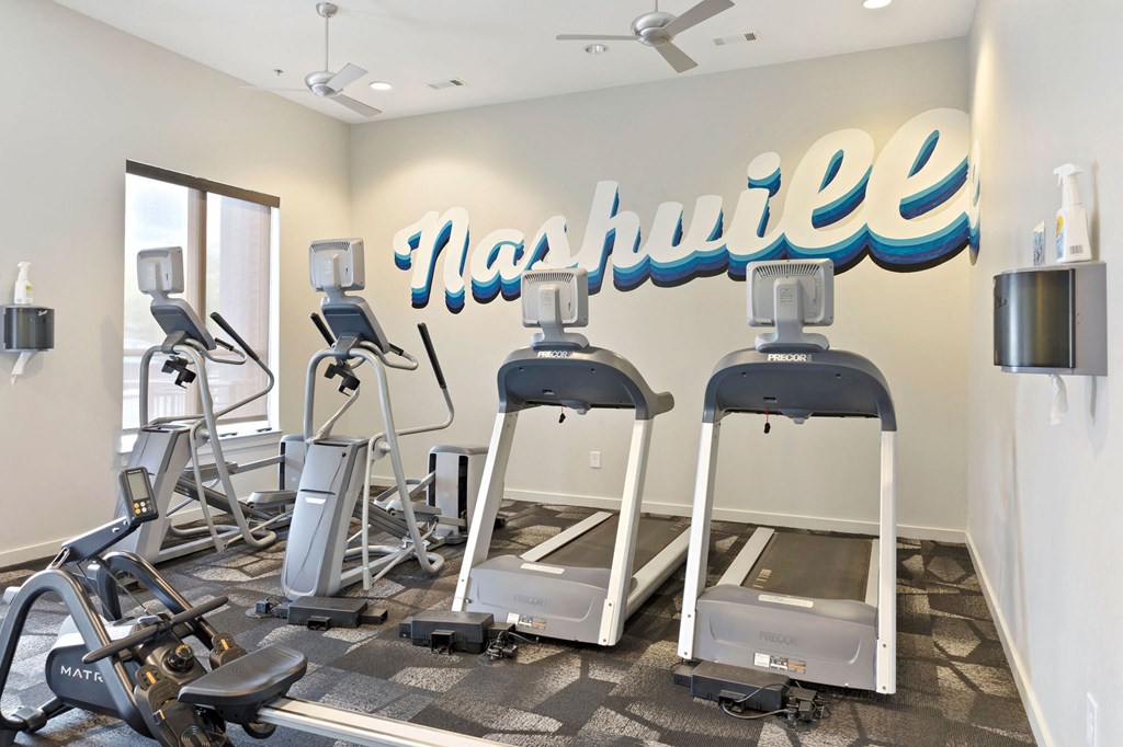 a gym with cardio machines and a sign on the wall