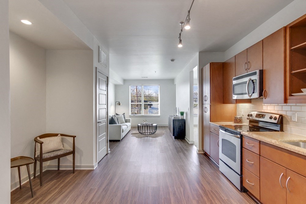 a kitchen and living room with wood flooring and wooden cabinets
