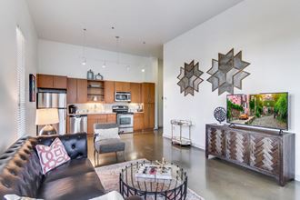 a living room with a leather couch and a kitchen with wooden cabinets