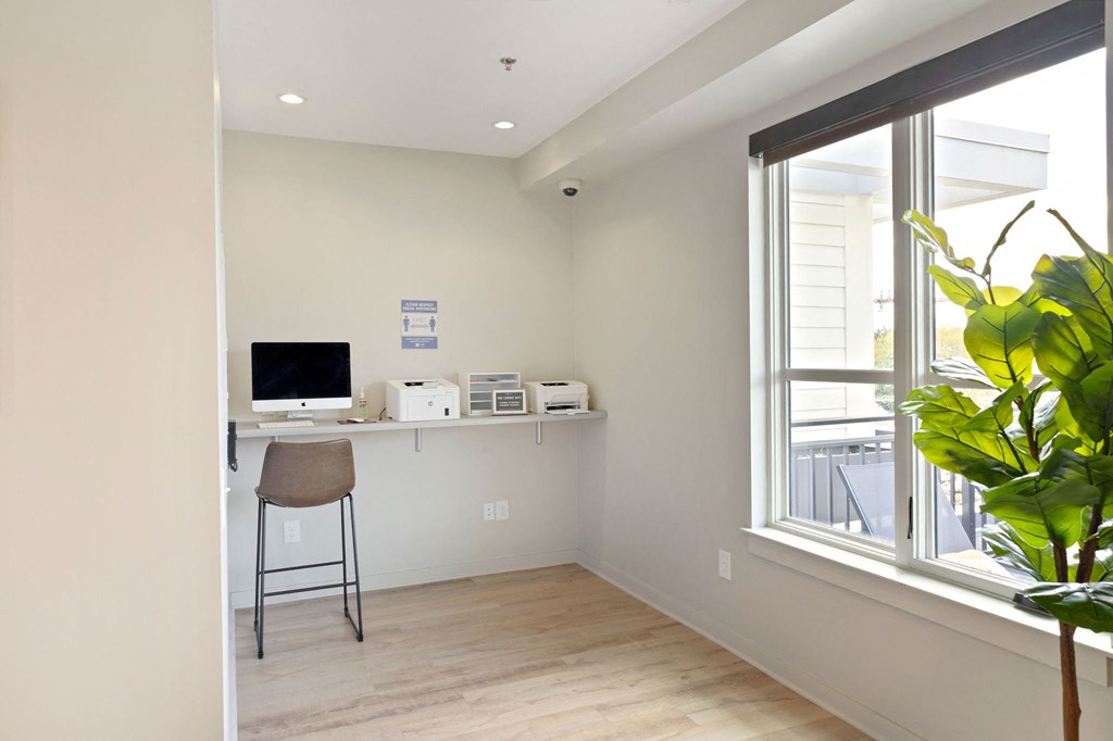 a home office with a computer and a desk in front of a window