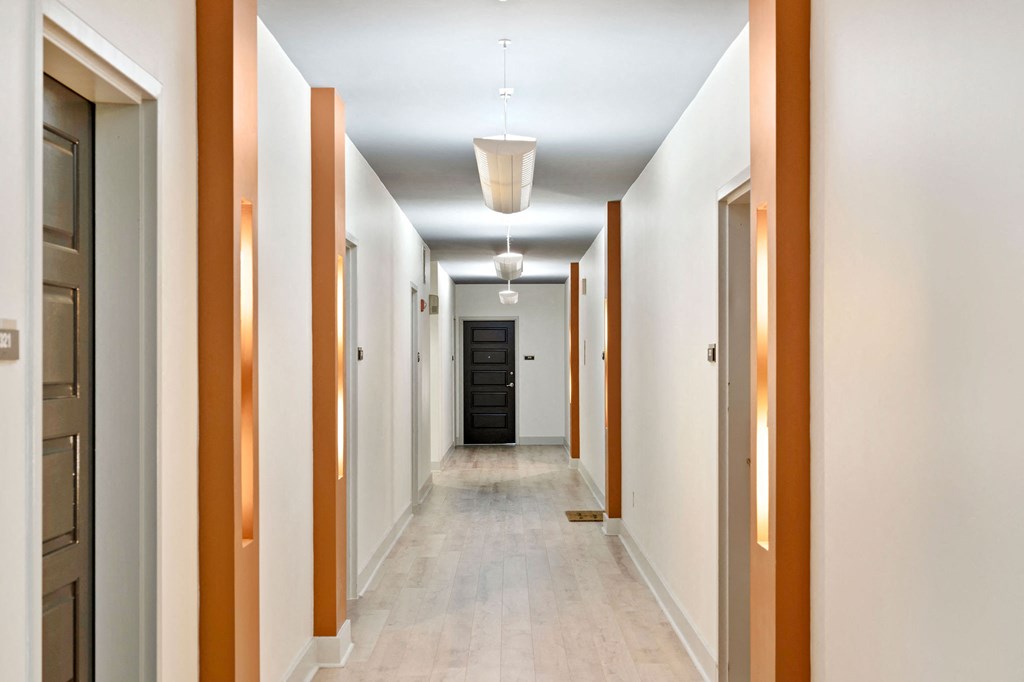 a long hallway with doors and white walls and a white tile floor