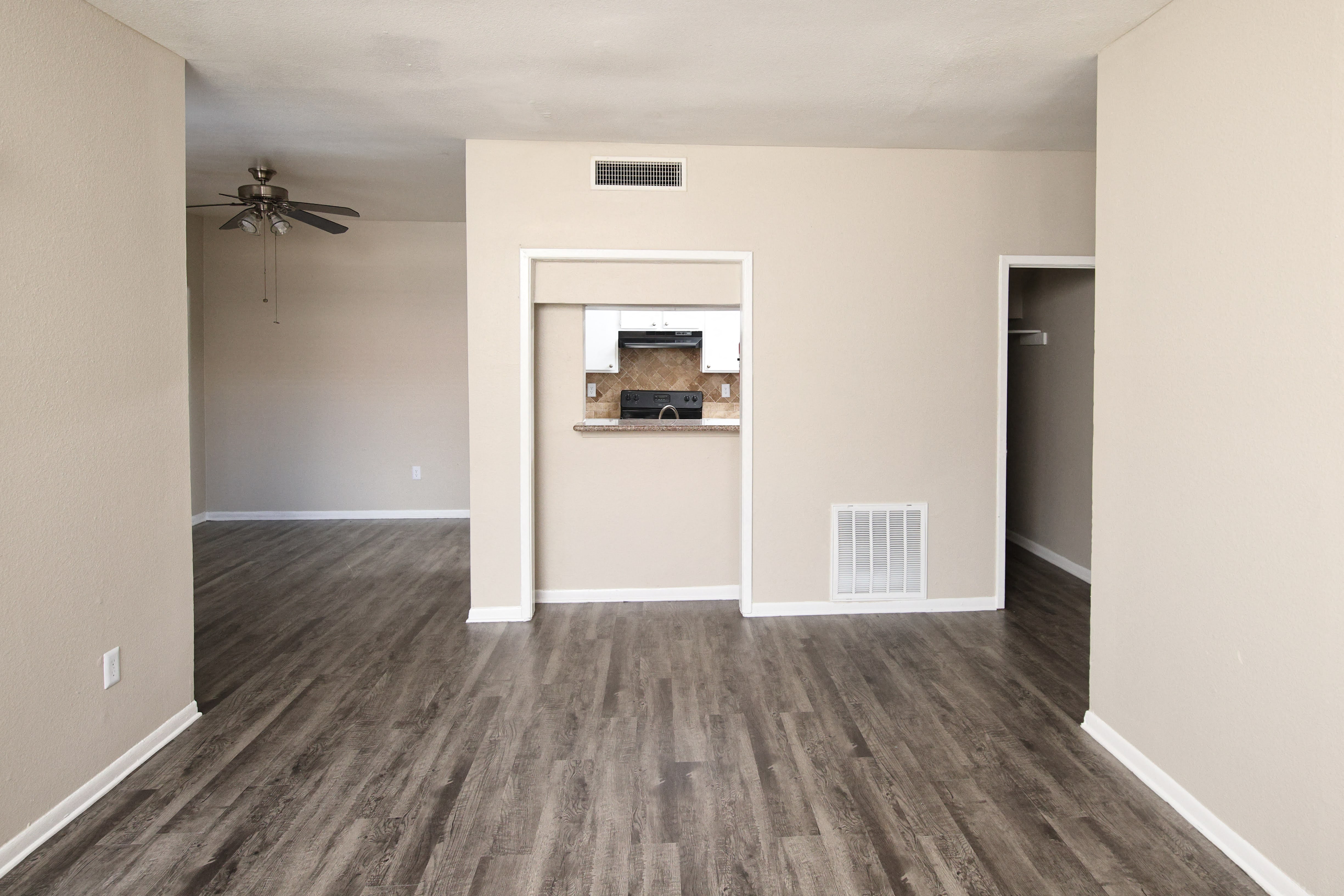 an empty living room with wood floors and a ceiling fan