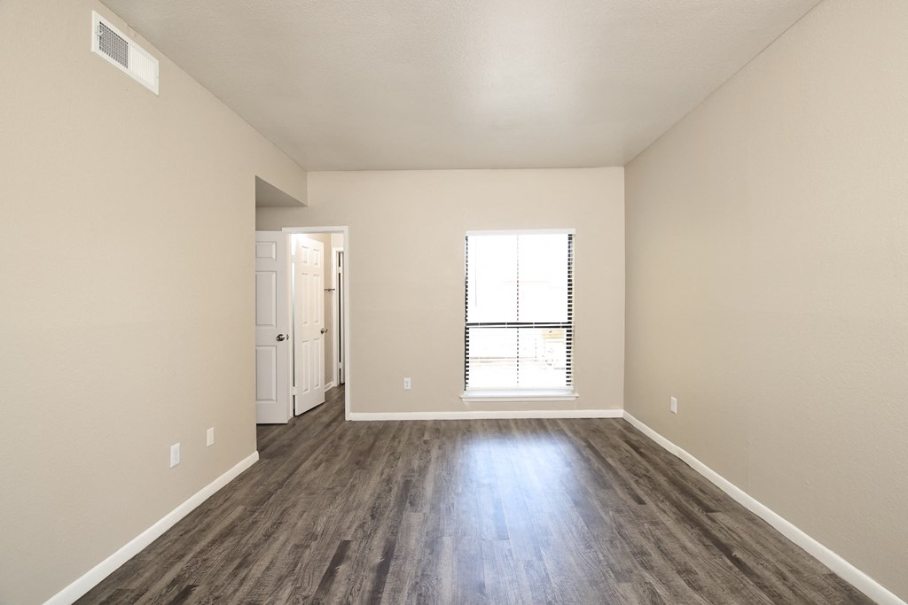 an empty living room with hard wood floors and a window