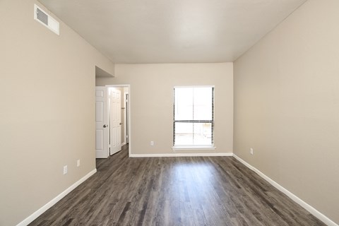 an empty living room with hard wood floors and a window