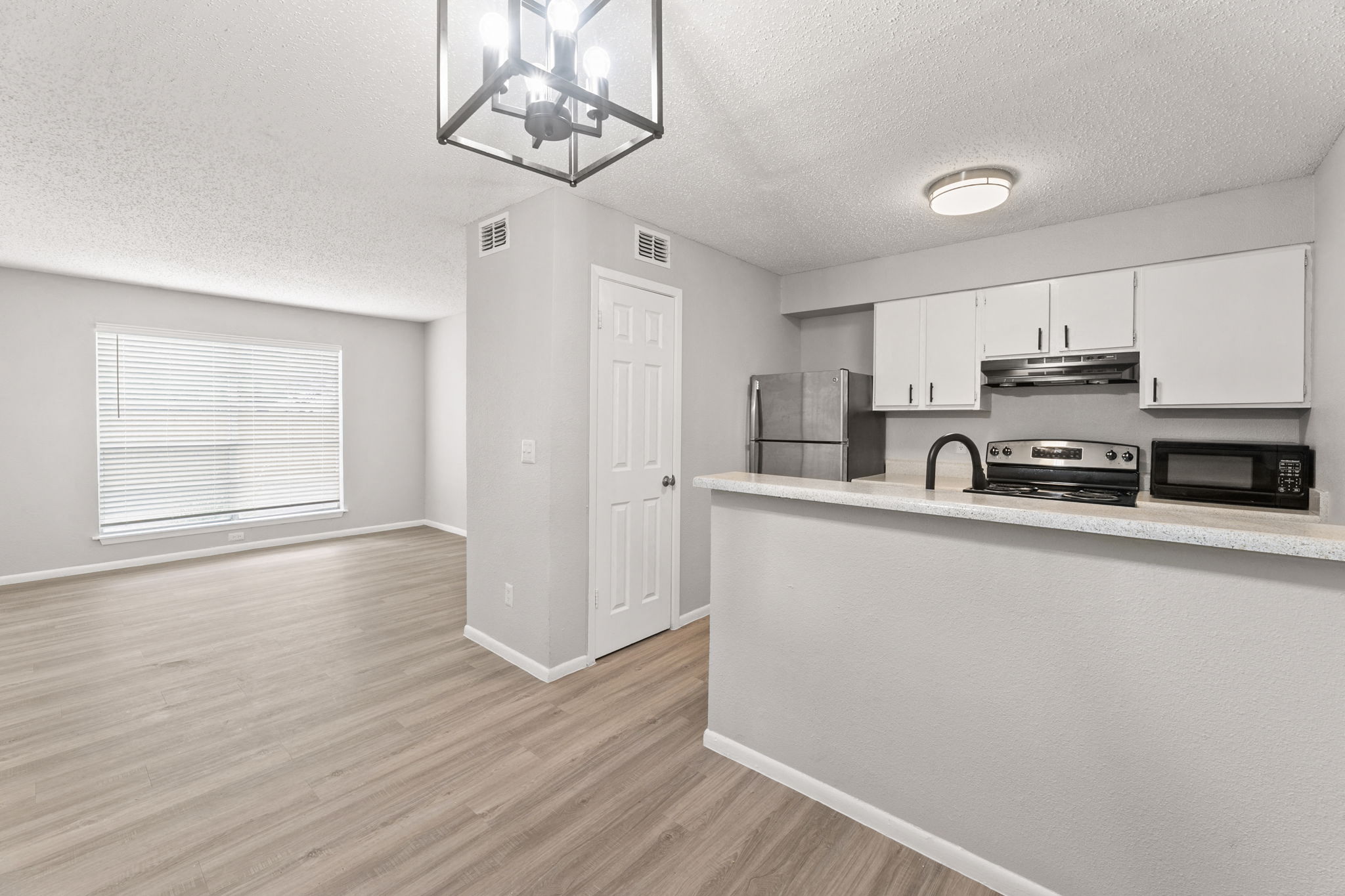 an open kitchen and living room with a large window and white cabinets