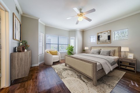 A bedroom with a large bed, a ceiling fan, and a rug on the floor.