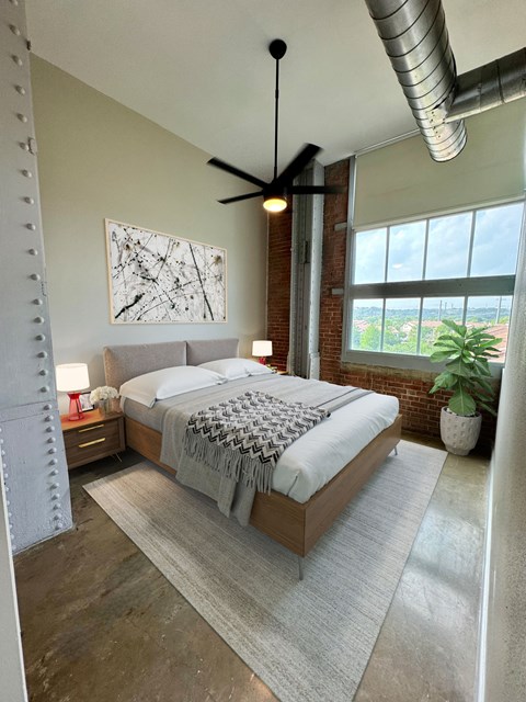 A bedroom with a large bed and a ceiling fan.