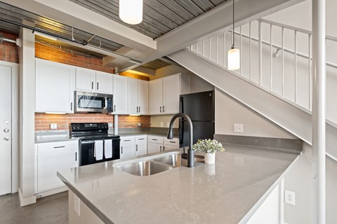 A kitchen with a stainless steel sink and white cabinets.