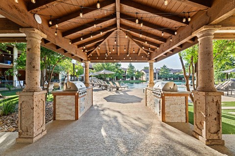 A wooden pergola with a gravel pathway underneath it.