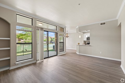 A spacious room with a sliding glass door leading to a balcony.