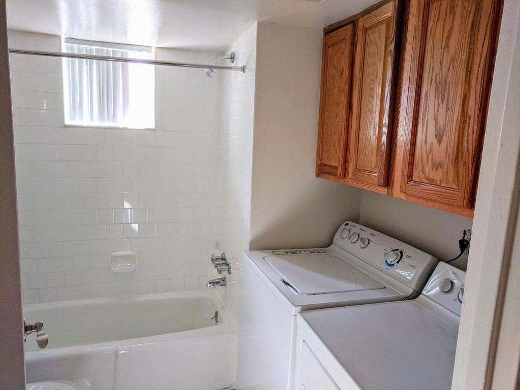 a small bathroom with a washing machine and a bath tub