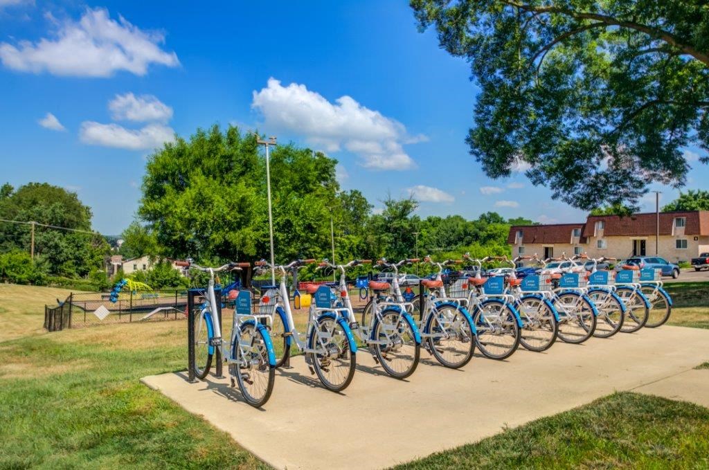 a row of blue bikes parked on a sidewalk