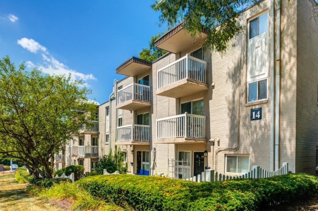 an apartment building with balconies and trees in the grass