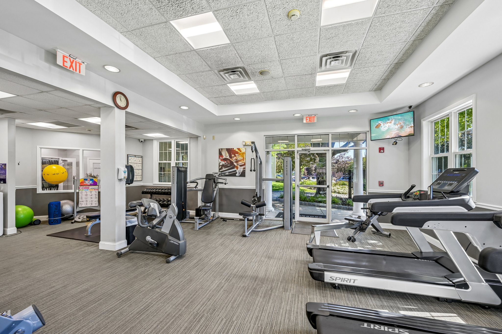A gym with treadmills, exercise equipment, and a green exercise ball.