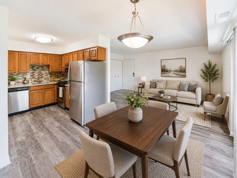 A kitchen with a refrigerator, dining table, and chairs.