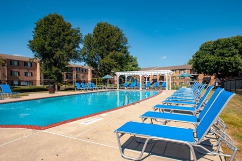 a swimming pool with blue lounge chairs next to a pool