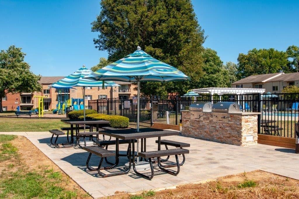 a picnic area with tables and umbrellas in front of a playground