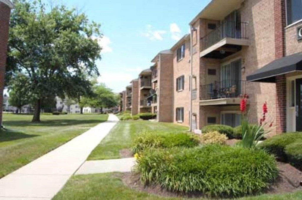 an apartment building with a sidewalk and grass