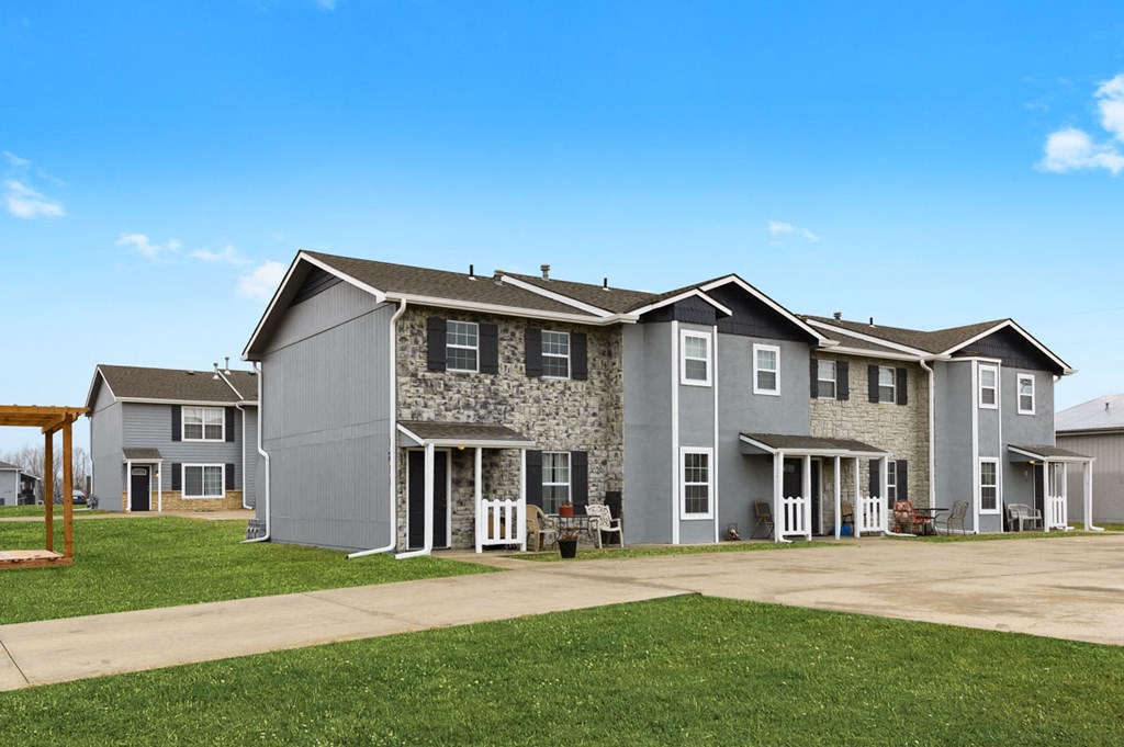 an apartment building with a driveway and a green lawn