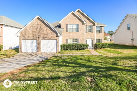 a brick house with two garage doors and a lawn