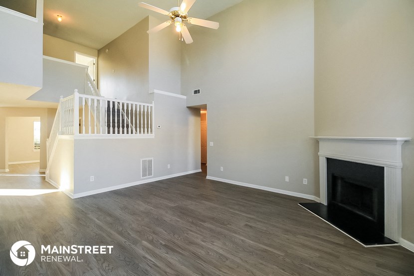 a living room with a fireplace and a ceiling fan