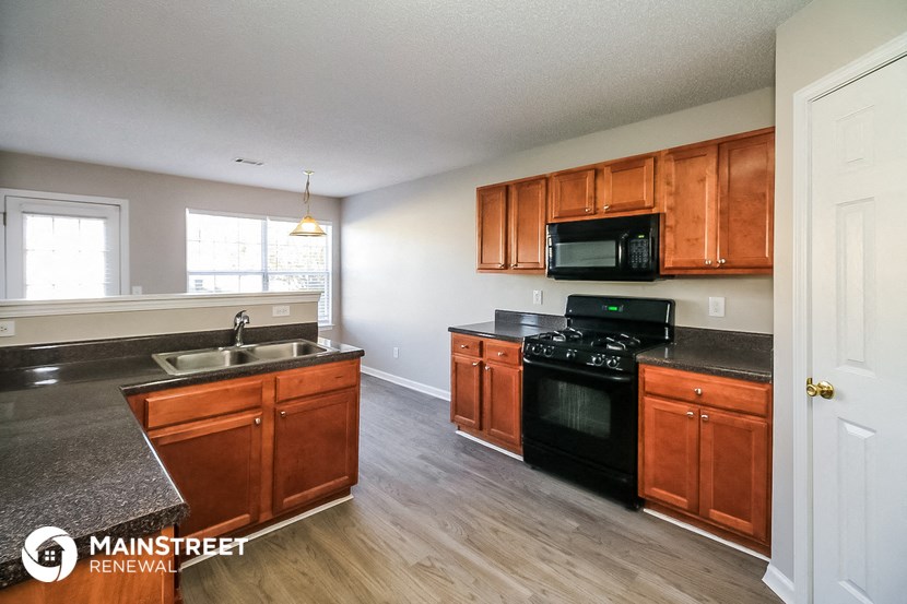 an empty kitchen with wooden cabinets and black appliances