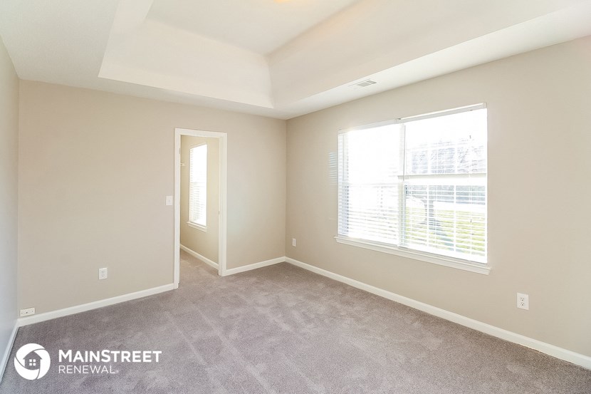 the spacious living room with a large window and carpeted flooring