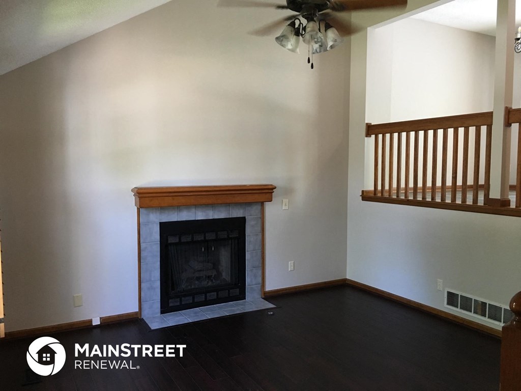 a living room with a fireplace and a ceiling fan