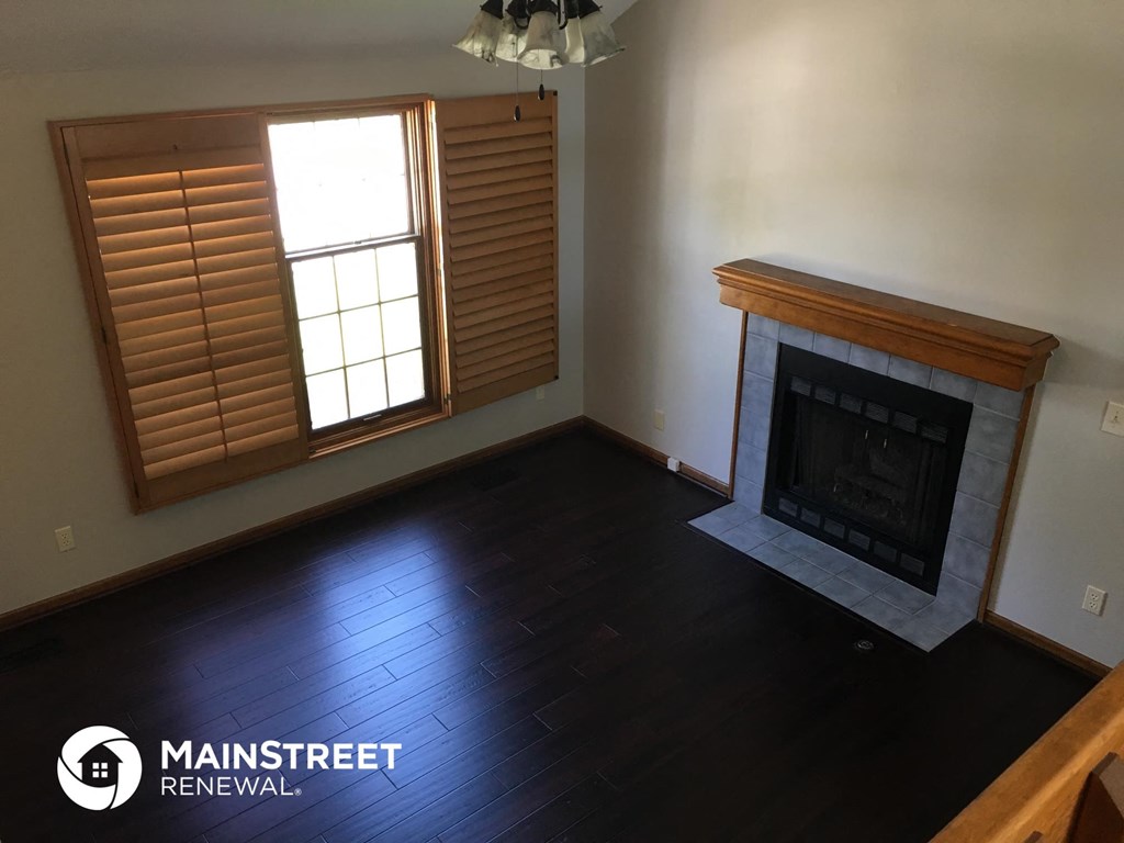 an empty living room with a fireplace and wooden floors