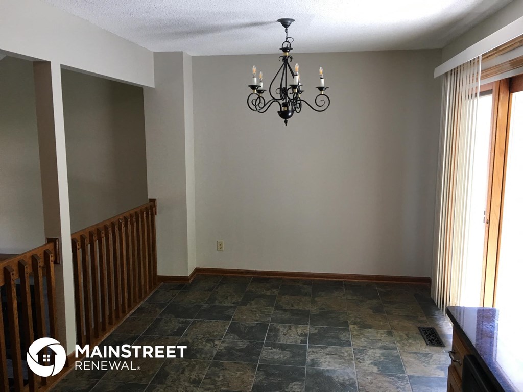 a dining room with gray walls and a chandelier